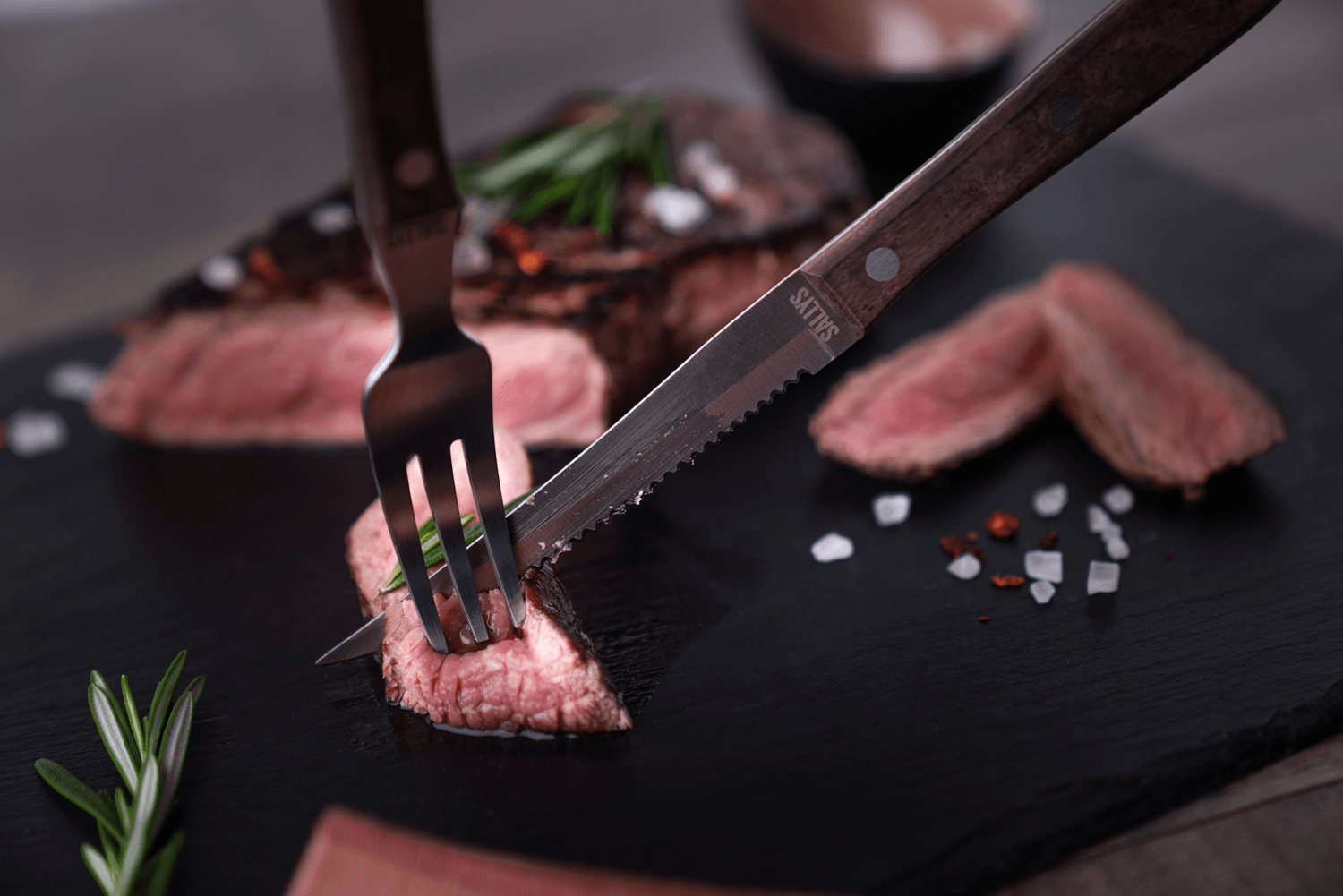 Mit dem Steak-Besteck wird ein Stück Fleisch geschnitten