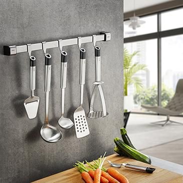 Eine silberne Küchenleiste mit Küchenwerkzeug hängt an einer Wand