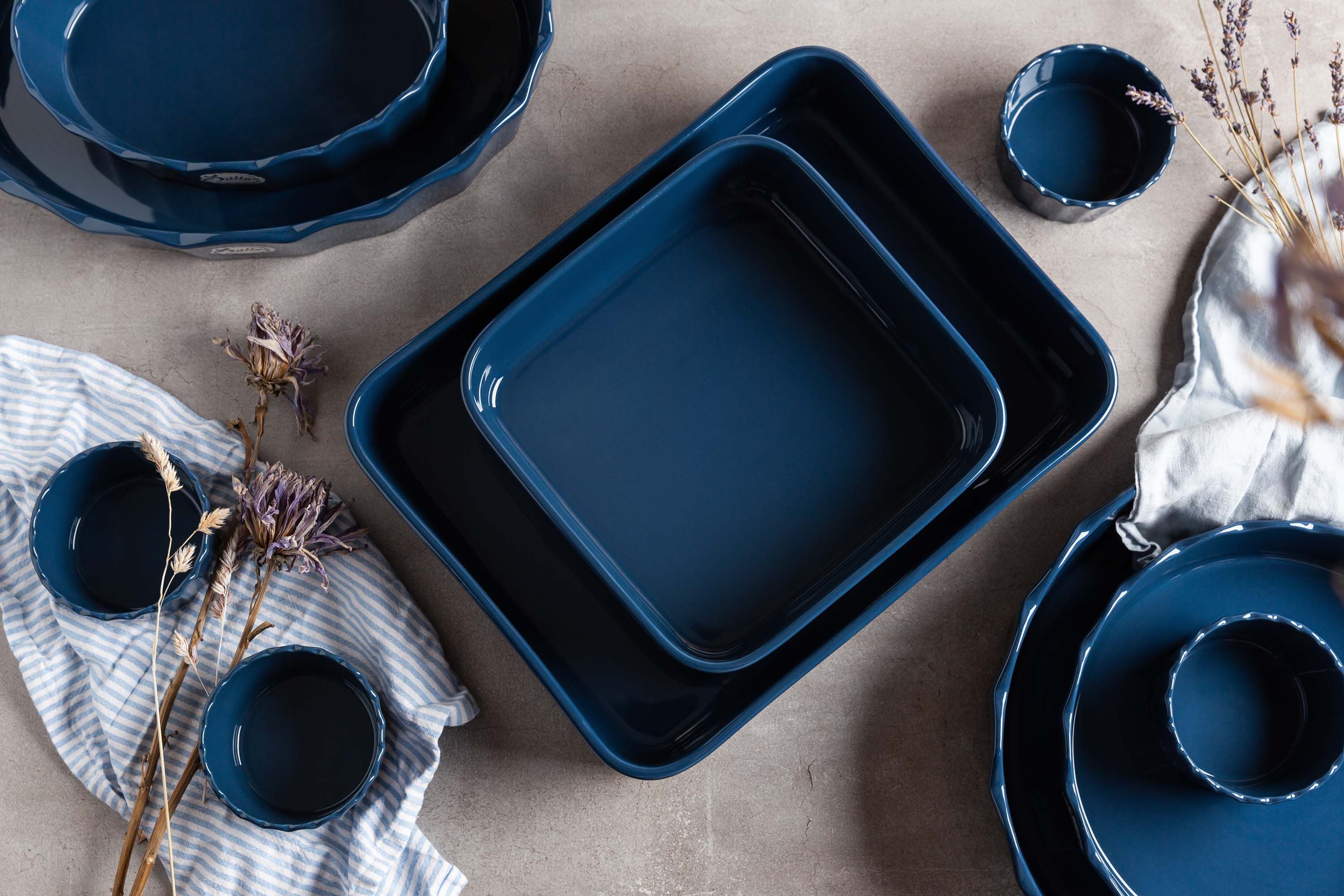 Mehrere blaue Stoneware-Ofenformen stehen auf einem Tisch