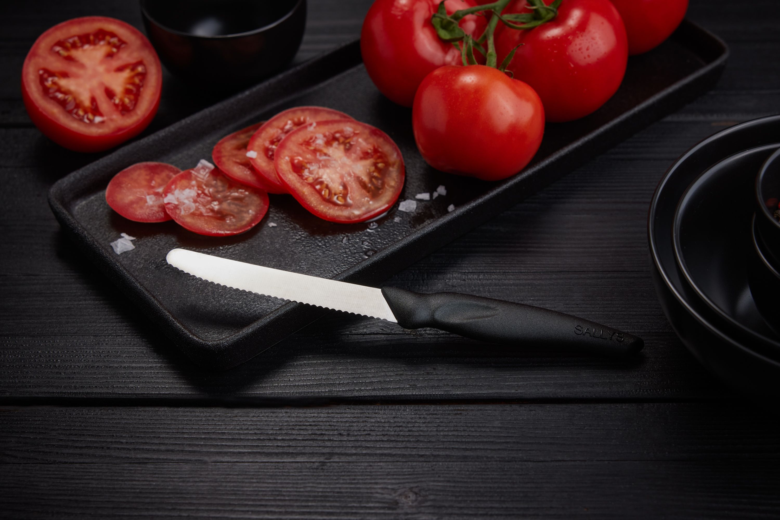 Ein schwarzes Powermesser liegt neben aufgeschnittenen Tomaten auf einem Tisch
