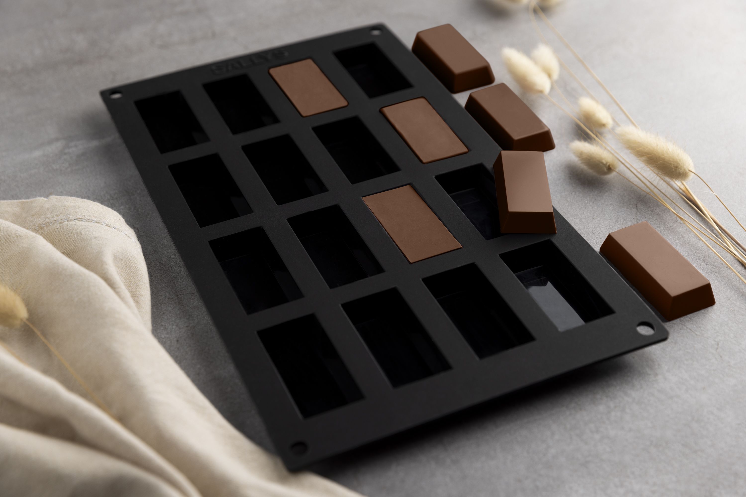 Eine Schokoladenform mit rechteckiger Schokolade liegt auf einem Tisch