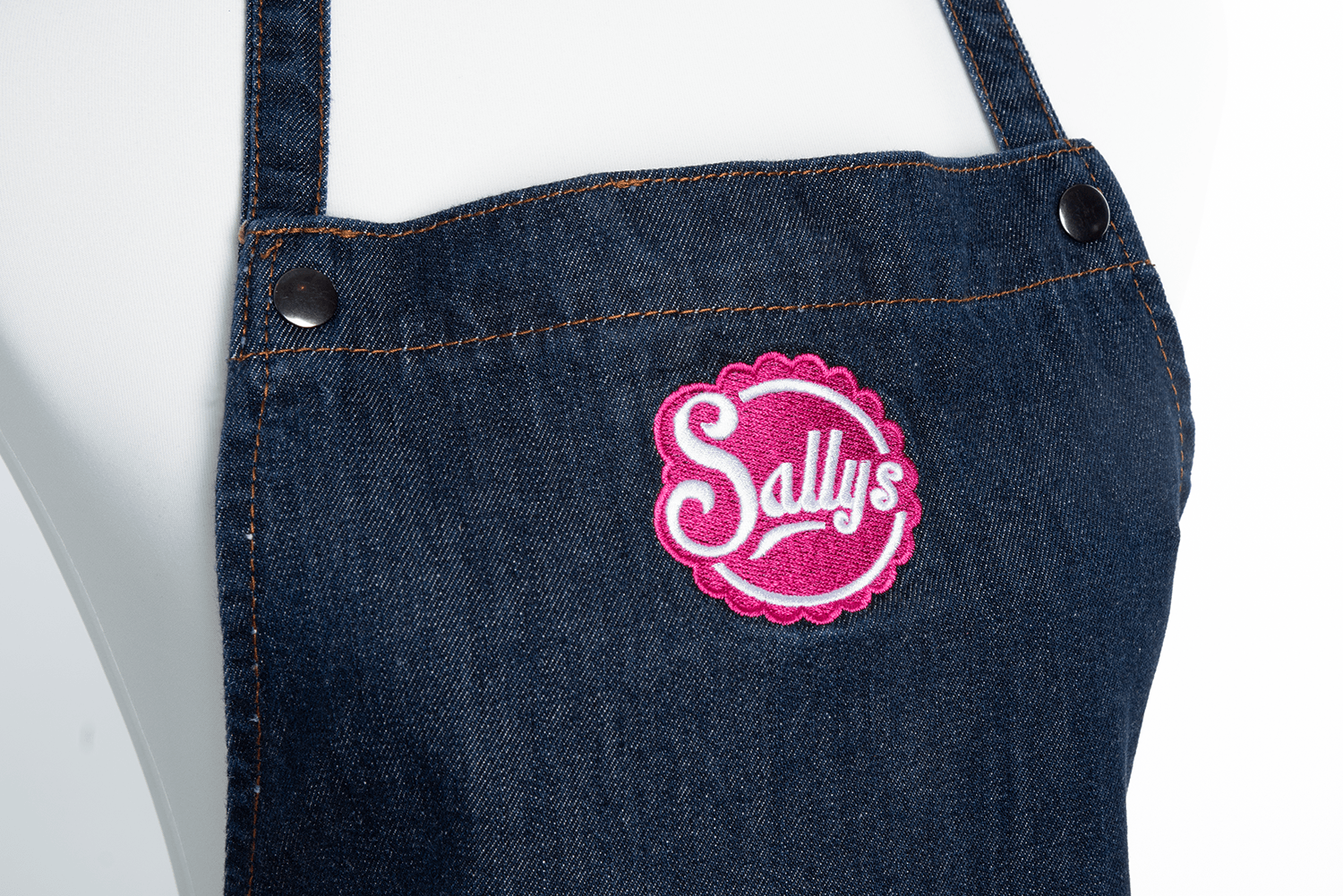 Nahaufnahme des Sallys Logos auf der Schürze in Jeansoptik