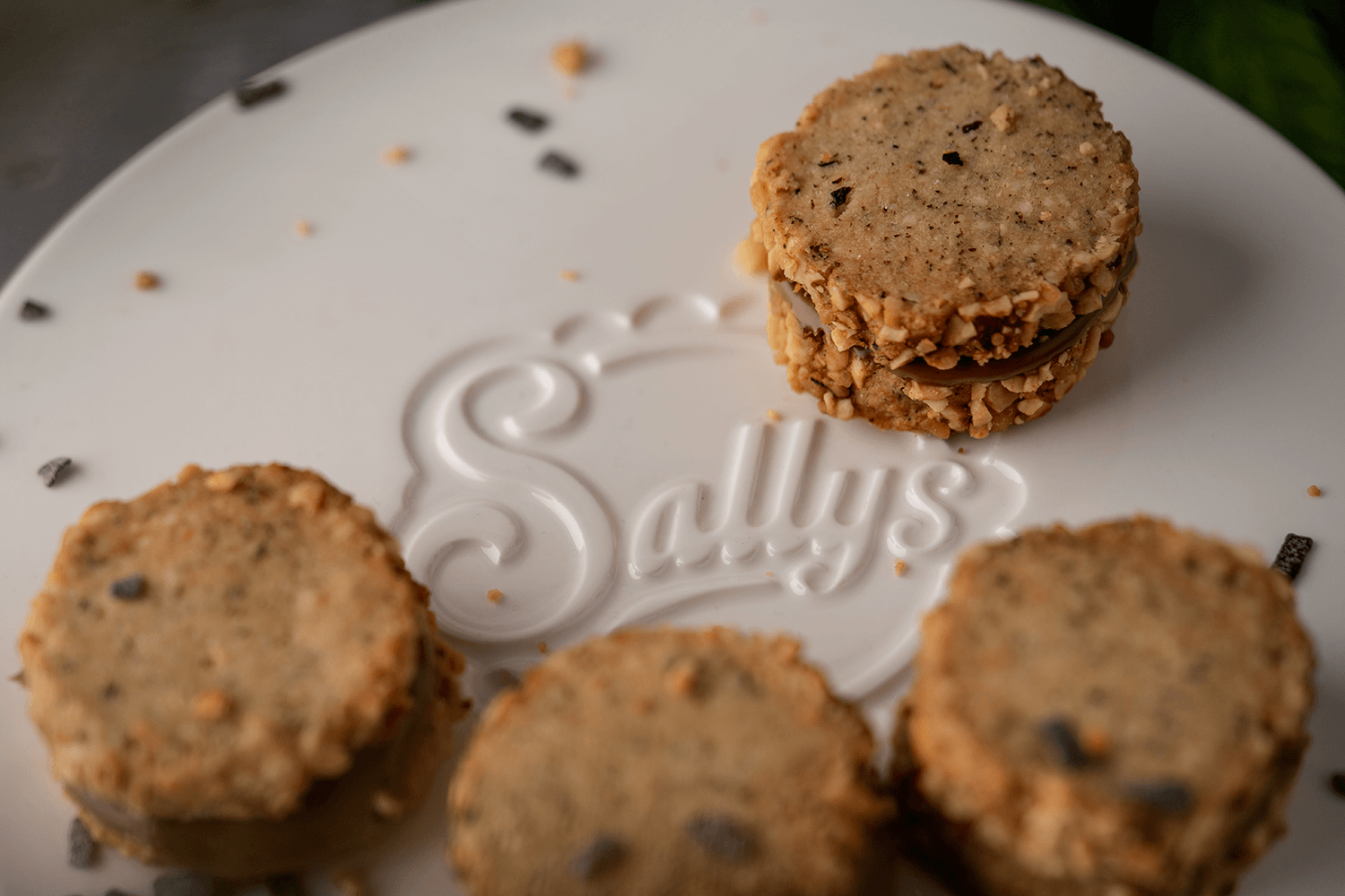 Kekse liegen auf einem weißen Tortenständer auf dem Sallys Logo