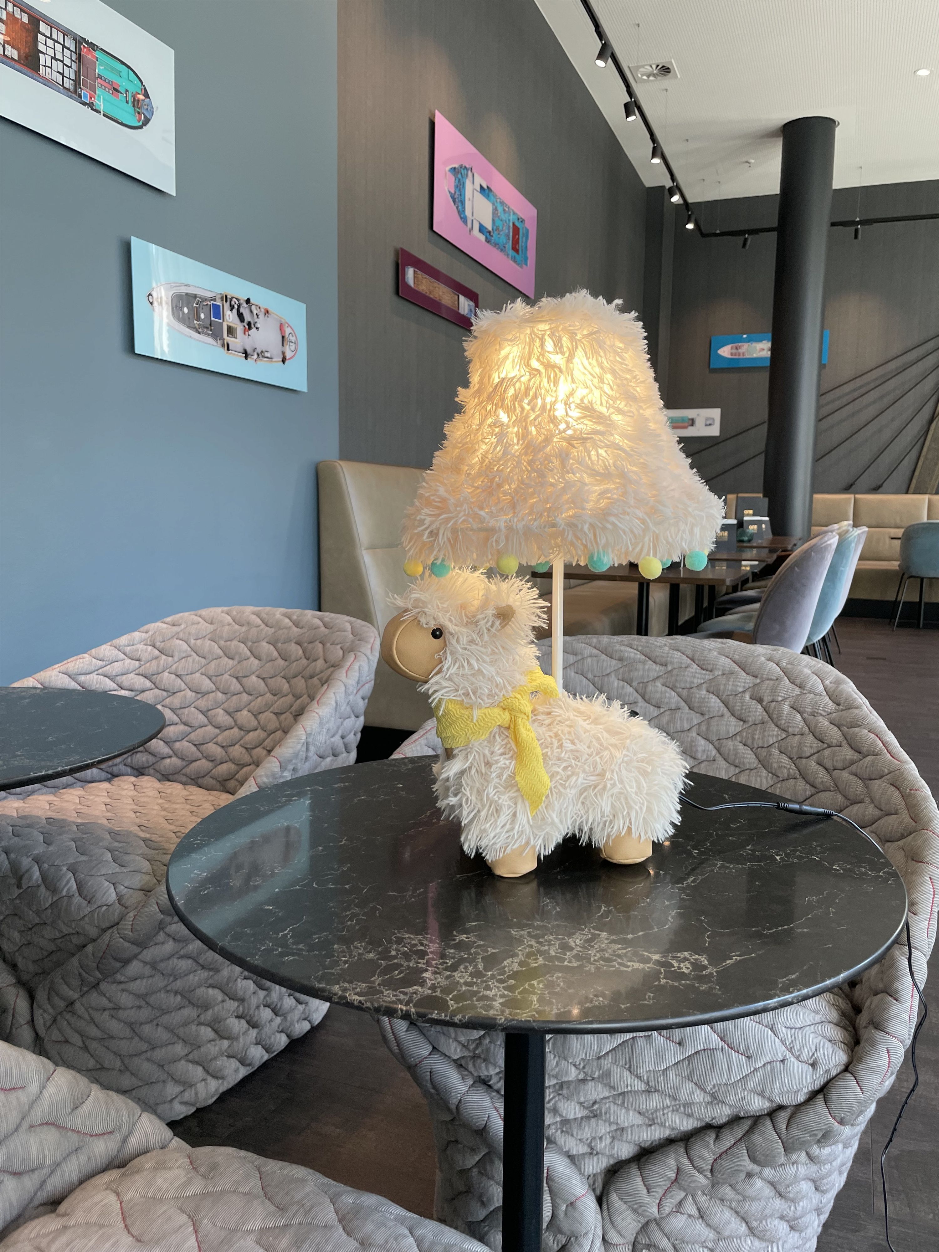 Eine Alpaka Stofftierlampe auf einem runden Tisch